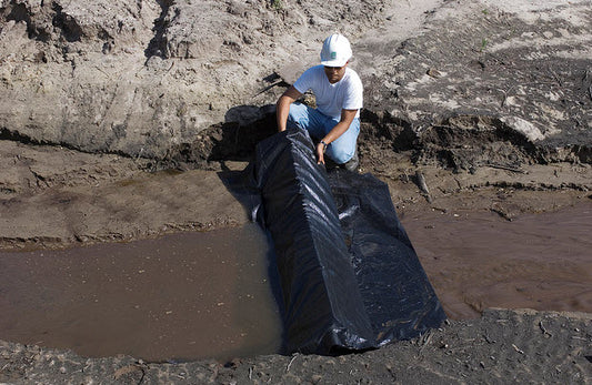 Construction stormwater compliance inspector examines sediment control BMP in a concentrated stormwater flow.